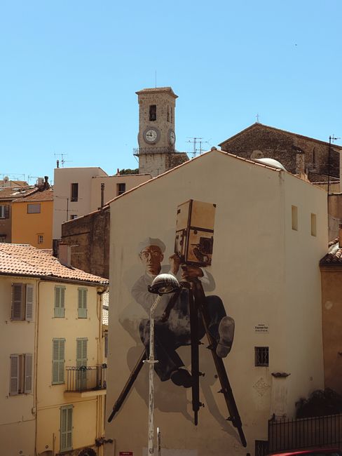 A striking mural in Cannes, featuring a street art camera against a backdrop of historic architecture.