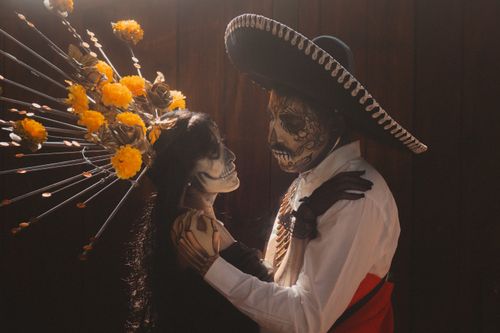 Free A vibrant Day of the Dead portrait featuring a couple in traditional Catrina and Catrin makeup and attire. Stock Photo