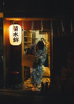 A person in a kimono outside a Japanese store at night in Kyoto, Japan.