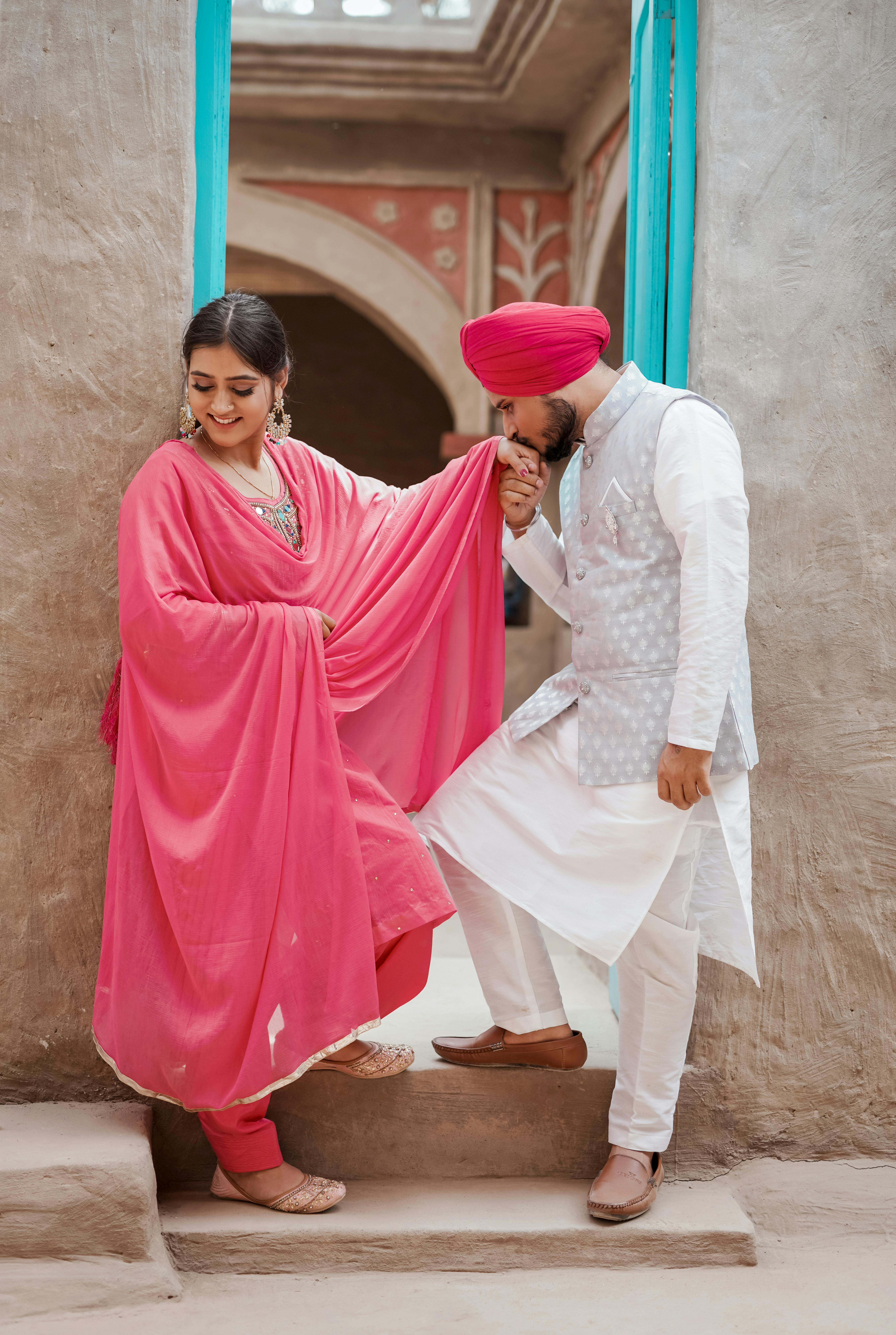 Charming couple in vibrant Indian clothing, sharing a tender moment indoors.