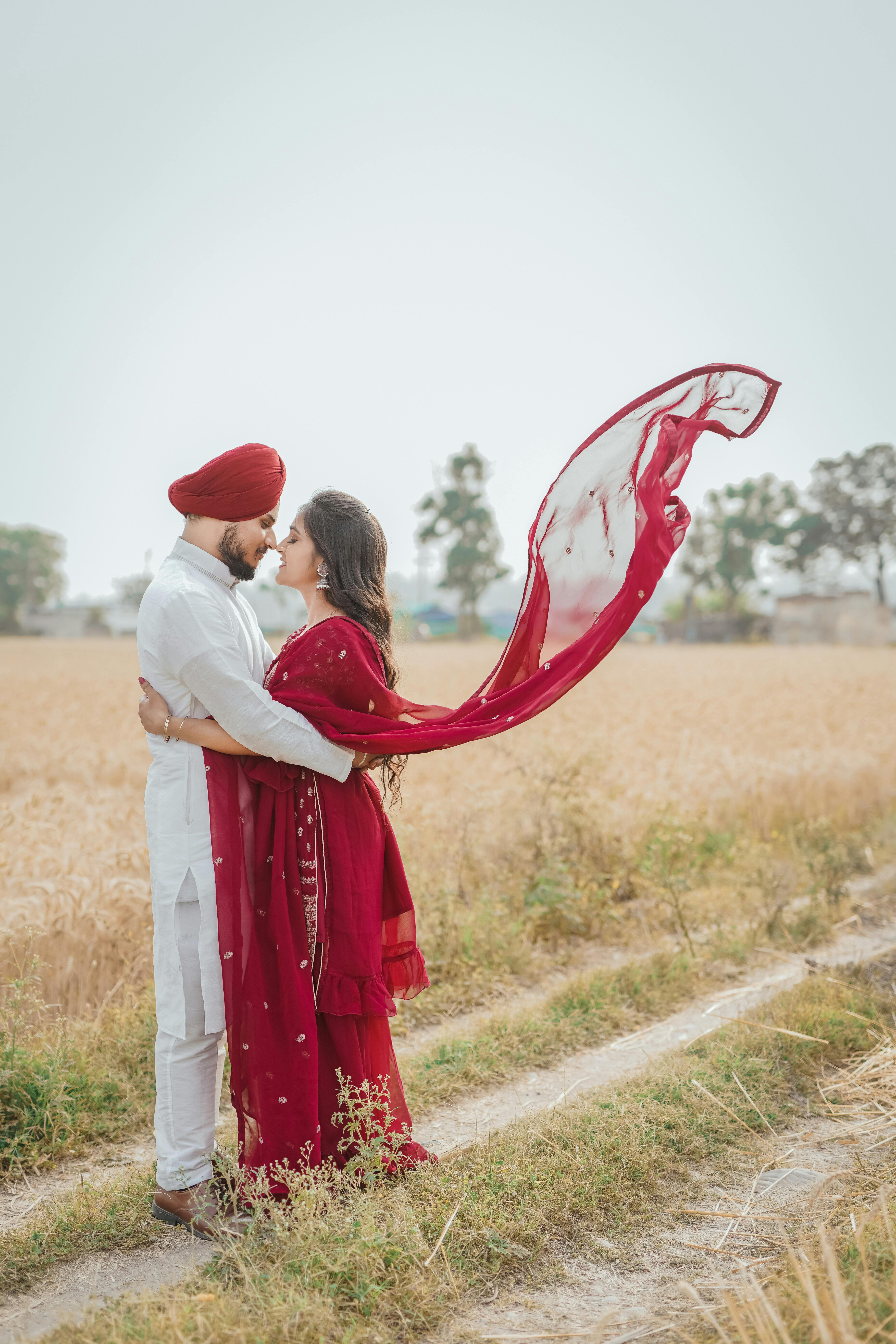 A couple in traditional attire embracing in a wheat field, symbolizing love and unity.