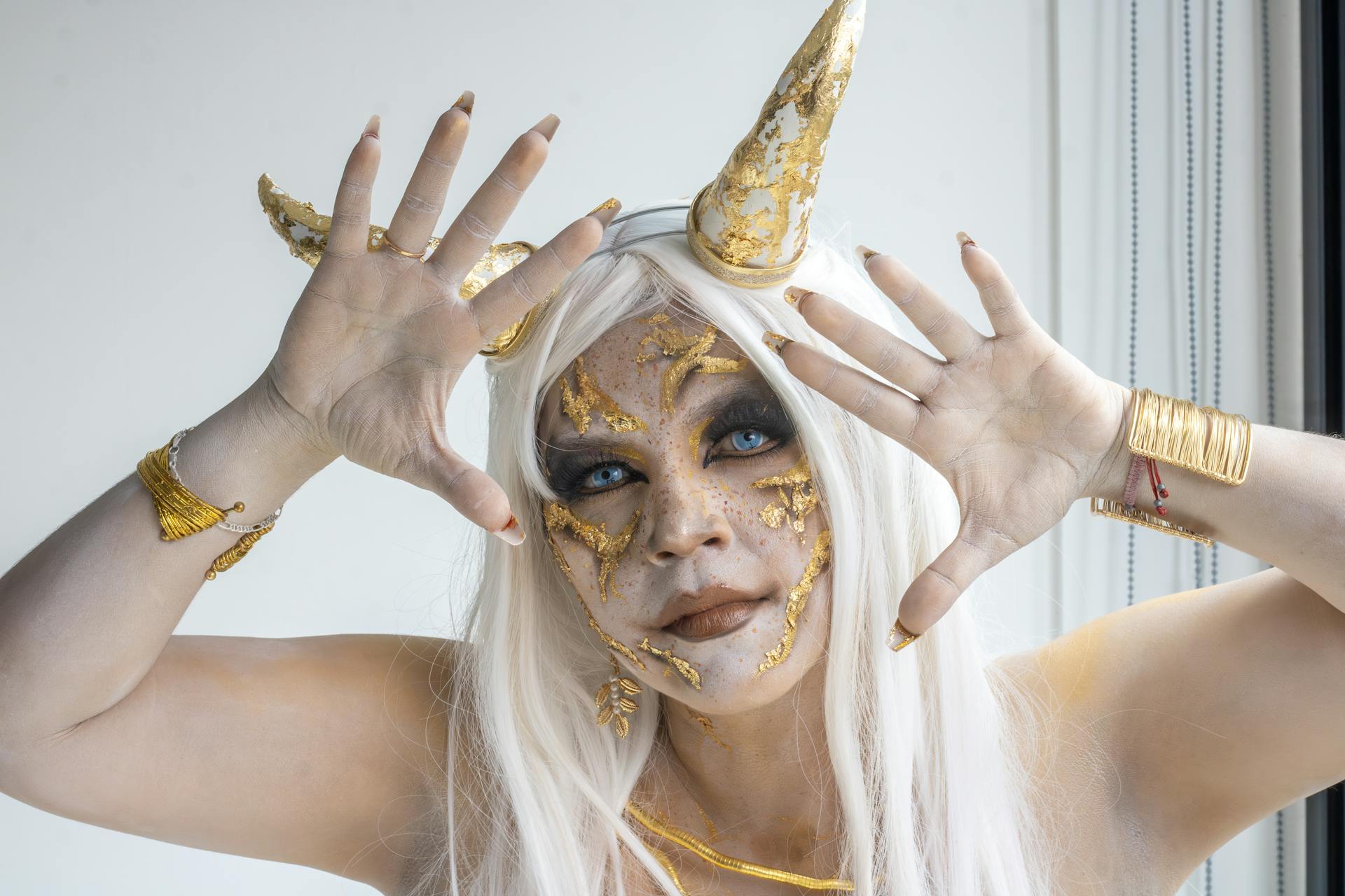 A woman in imaginative cosplay with gold face accents and horns in a fantasy theme.