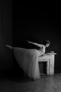 A graceful ballerina elegantly performs a classic pose on pointe against a dark backdrop.