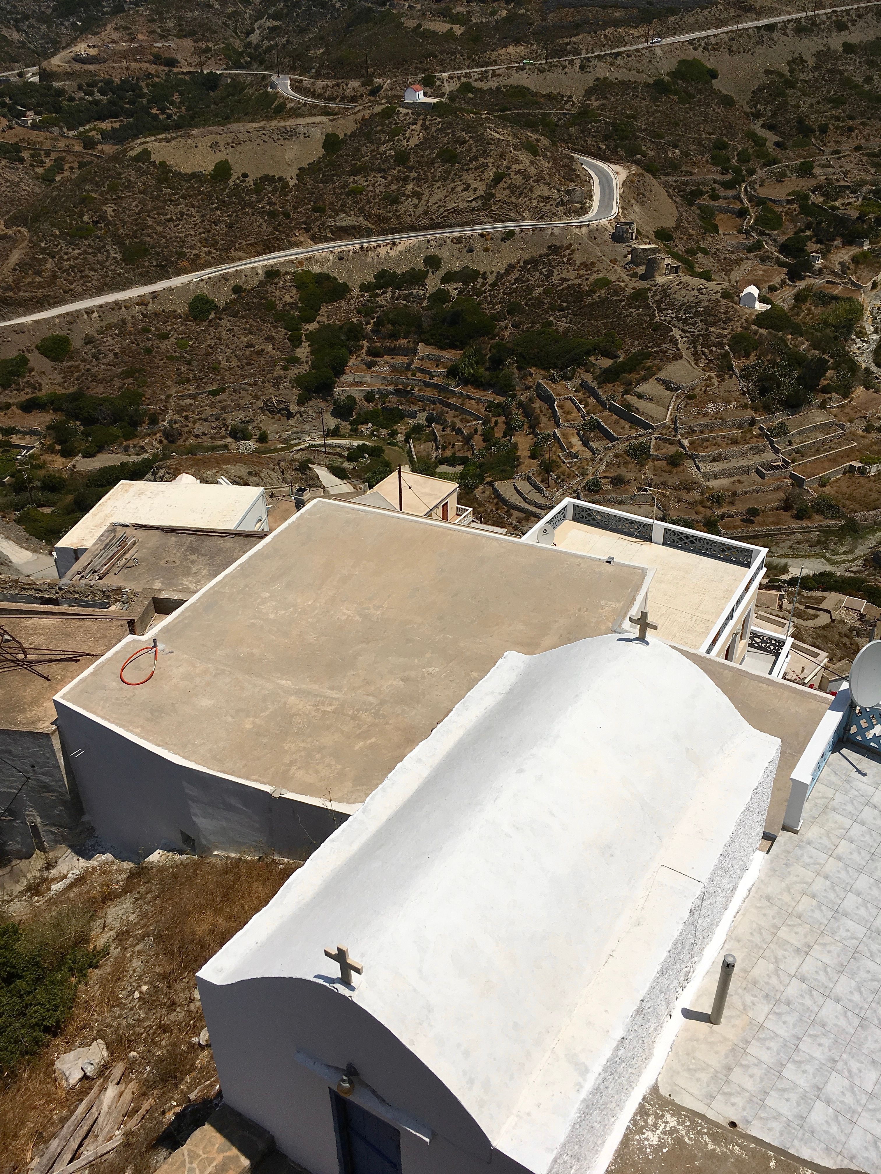 Capture of whitewashed buildings in the Greek landscape with winding roads.