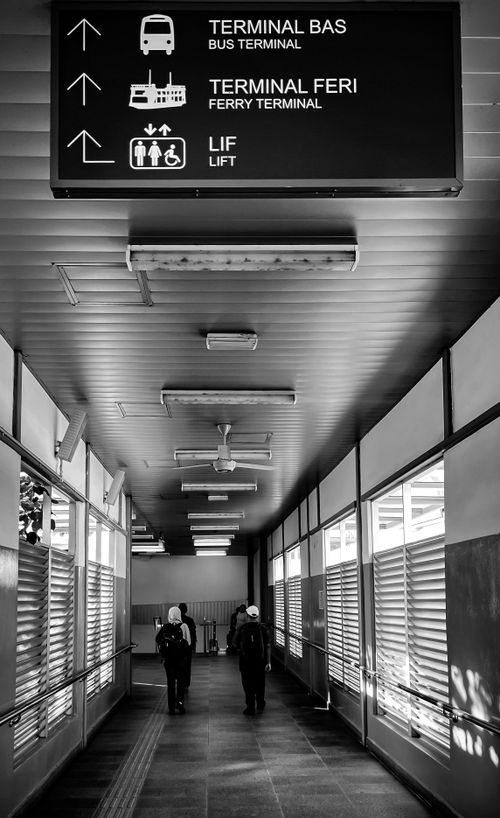Free Black and white image of a corridor leading to a bus and ferry terminal, highlighting modern transportation design. Stock Photo