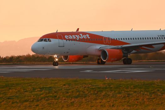 EasyJet airplane taxiing on the runway during a vibrant sunset.