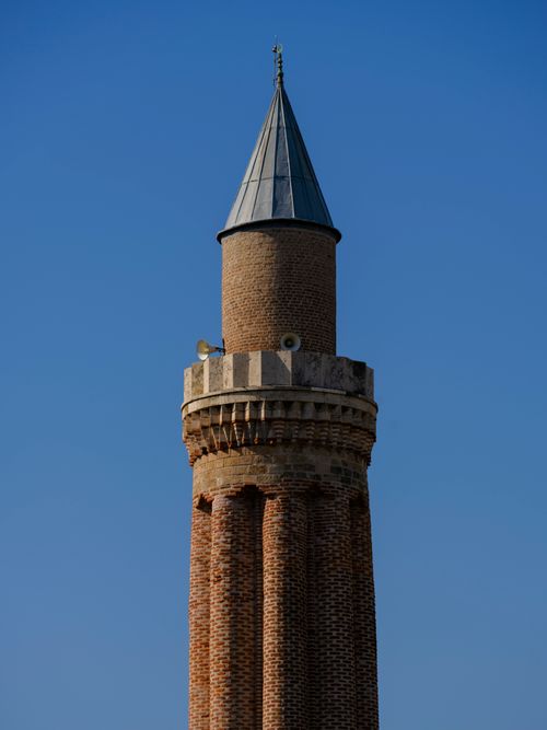 Free A detailed view of an ancient brick minaret with clear blue sky in the background, showcasing Islamic architecture. Stock Photo