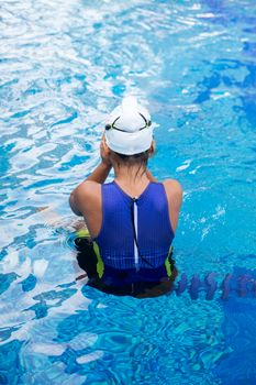 Female athlete in swimsuit and cap getting ready by the pool in Ho Chi Minh.