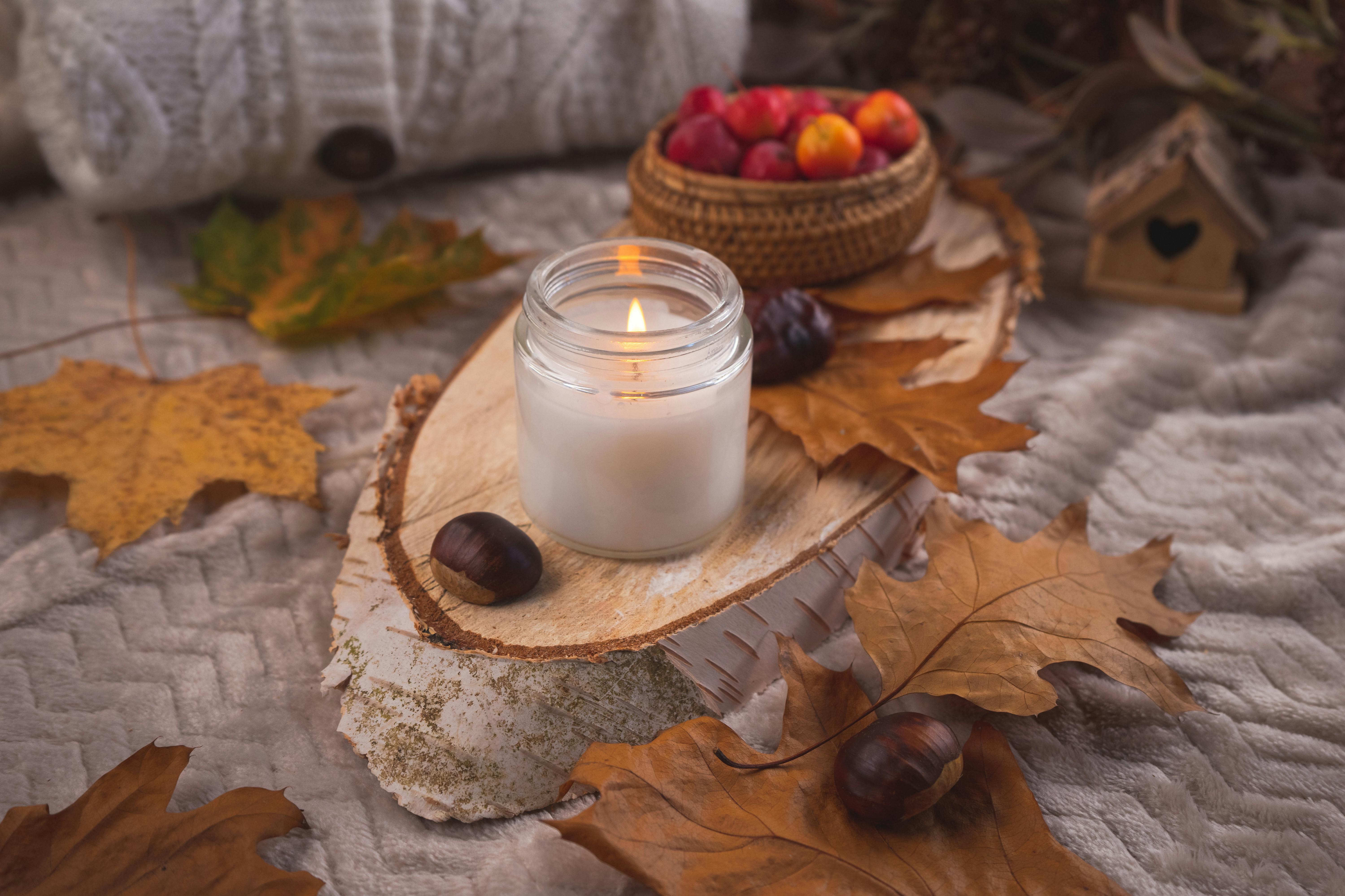 Warm autumn scene with candle, leaves, chestnuts, and cozy textures.