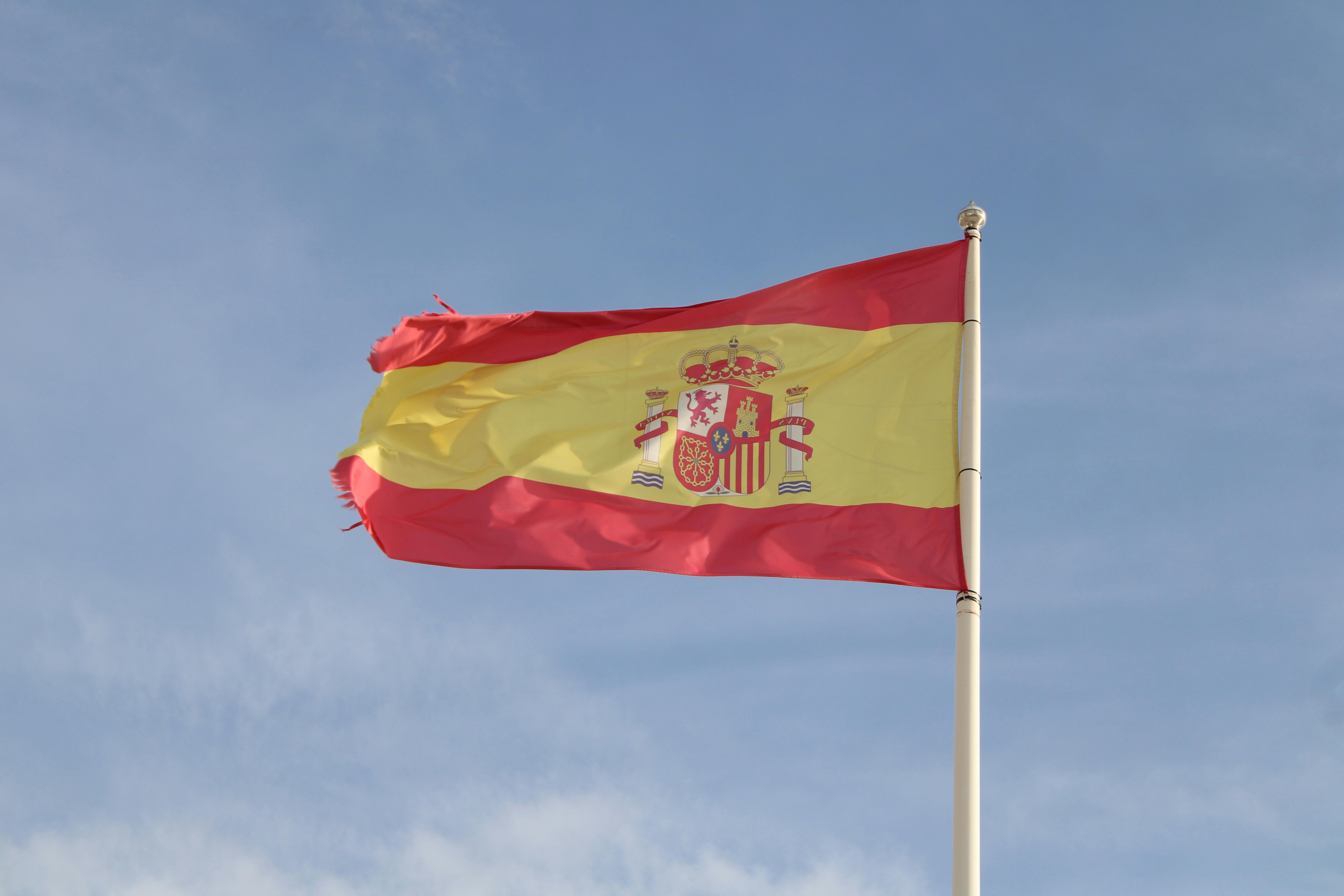 Drapeau espagnol flottant haut sur un mât contre un ciel clair en Andalousie, Espagne.