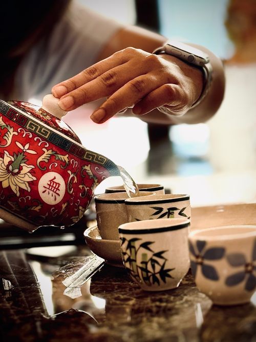 Free Close-up of a red teapot pouring tea into traditional cups, showcasing elegance and culture. Stock Photo