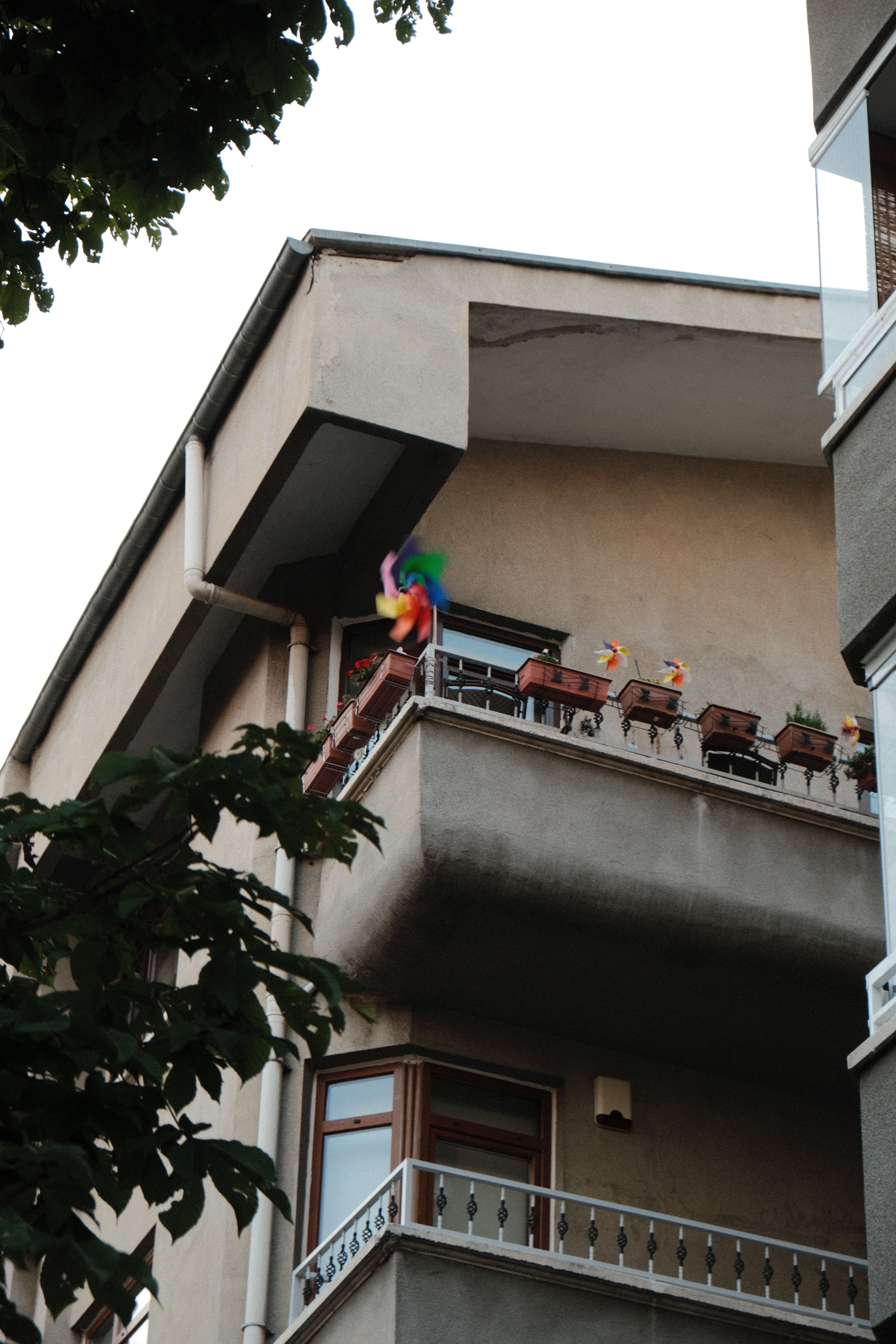 Urban apartment balcony with vibrant decor and potted plants, viewed from below.
