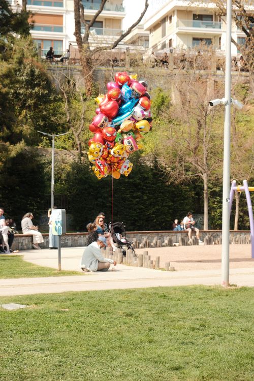Free A vibrant collection of balloons in a bustling urban park scene. Stock Photo