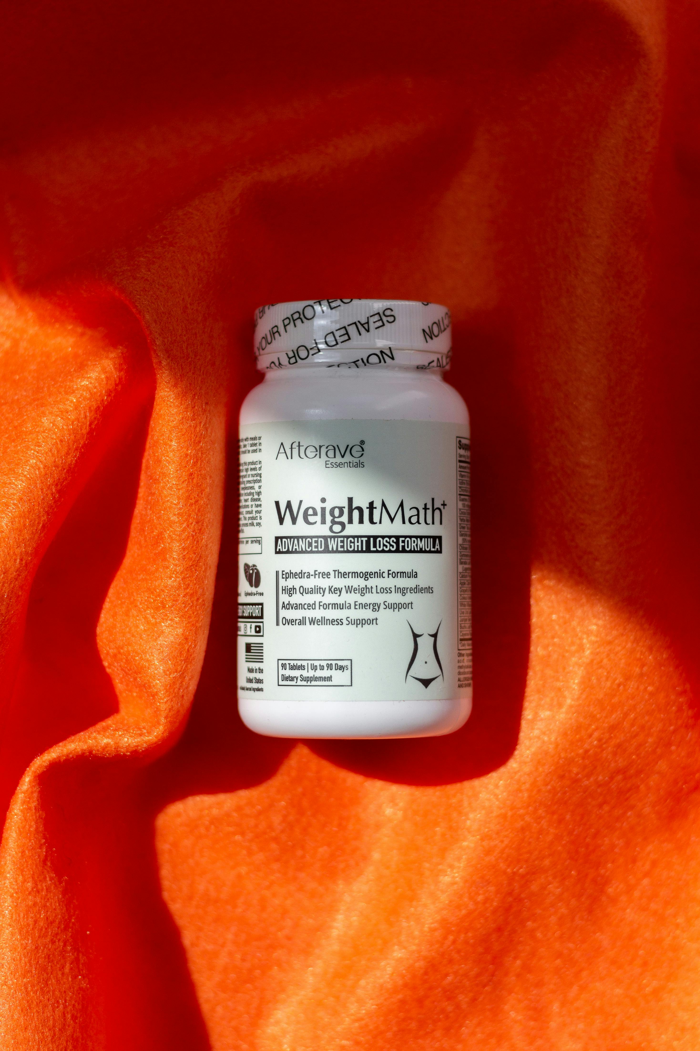 Weight loss supplement bottle on vibrant orange fabric, promoting diet and metabolism boost.
