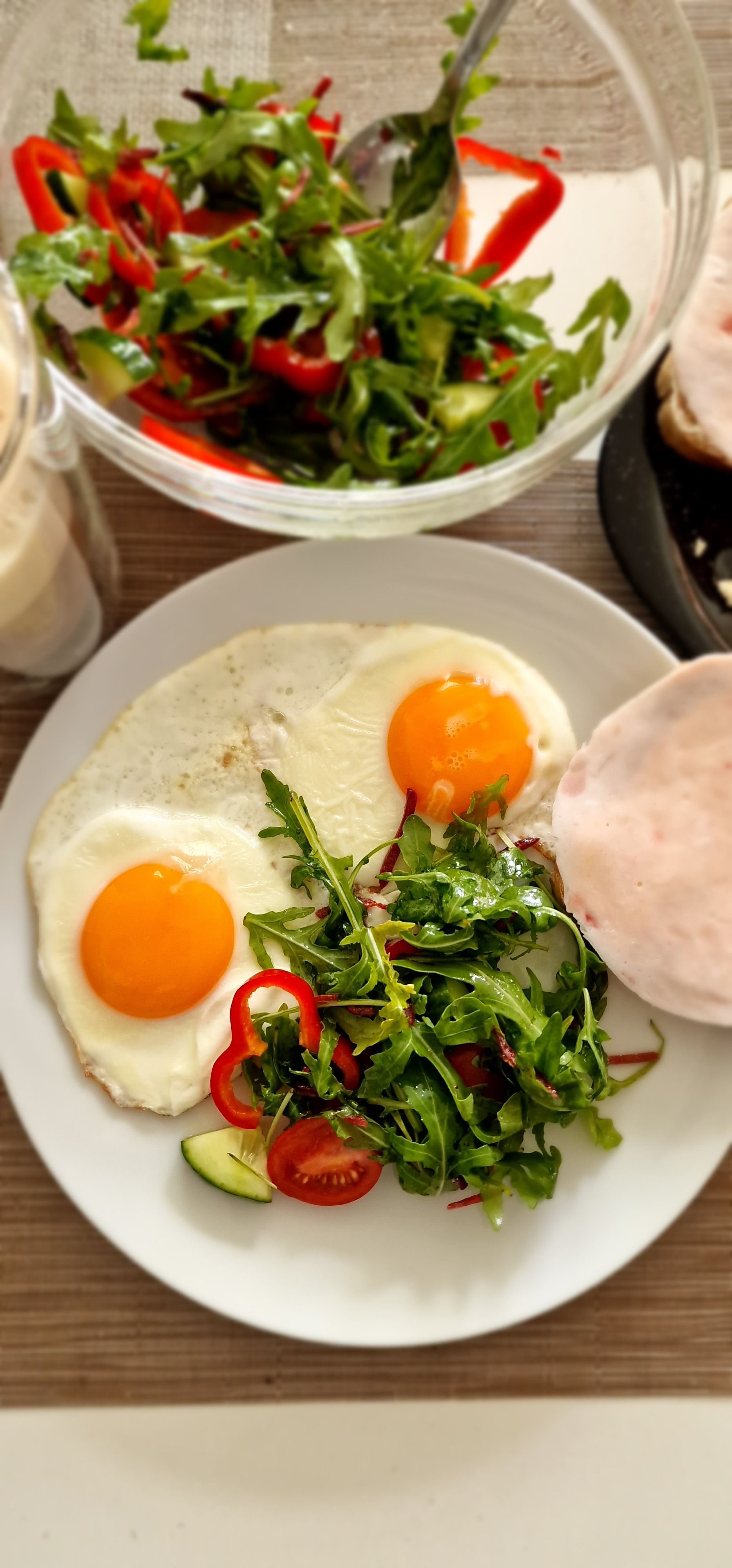 Tasty brunch with fried eggs, fresh salad, and sliced ingredients.
