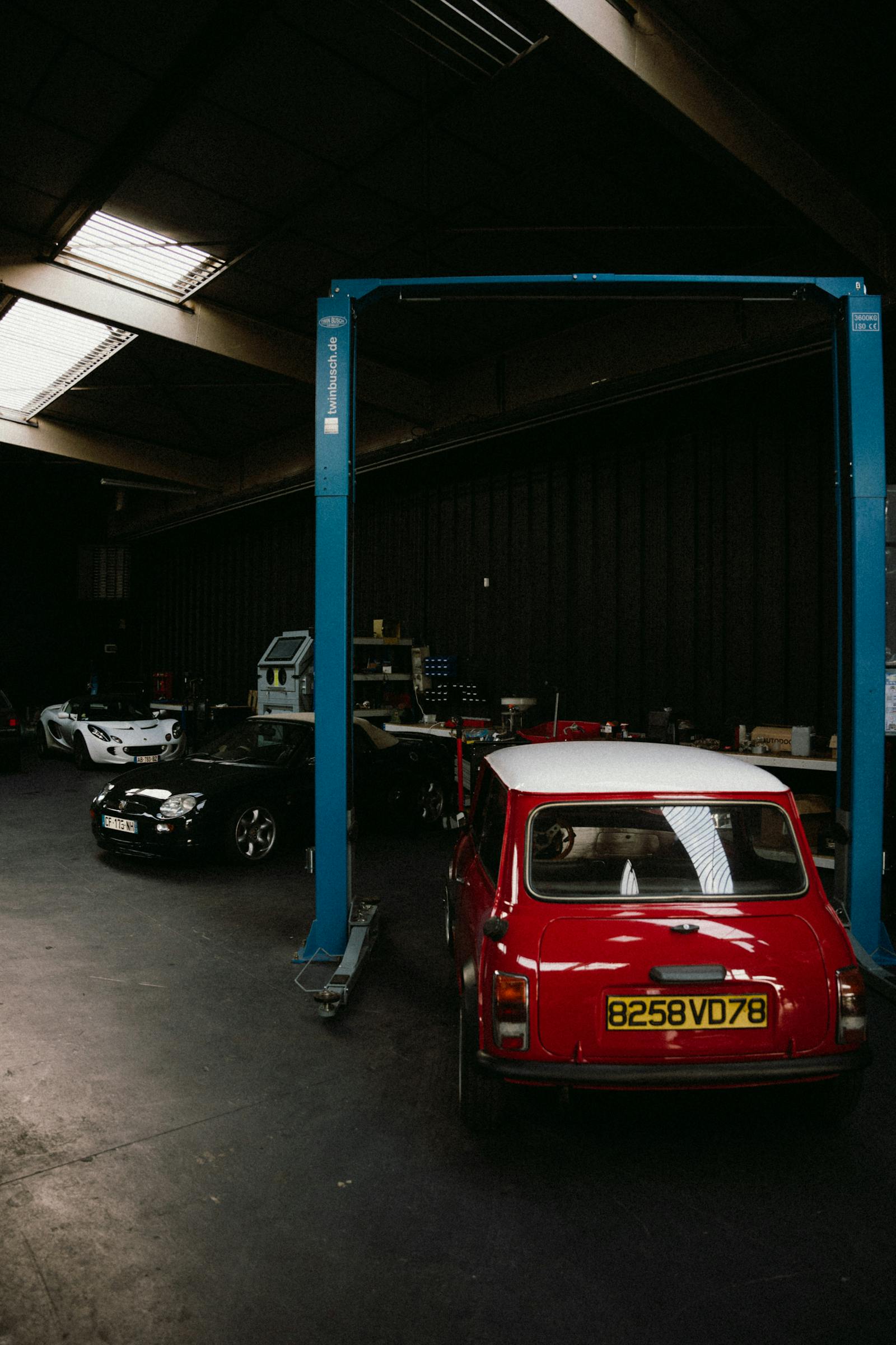 Vintage car in a restoration workshop with tools and equipment.