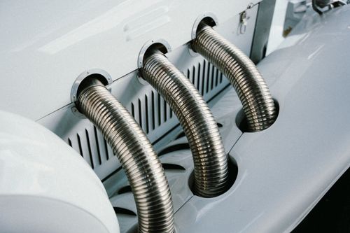 Free Close-up of a vintage car's chrome exhaust pipes, showcasing elegance and mechanical design. Stock Photo