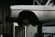 A classic car is elevated on a lift in a professional auto repair garage, showcasing its undercarriage.