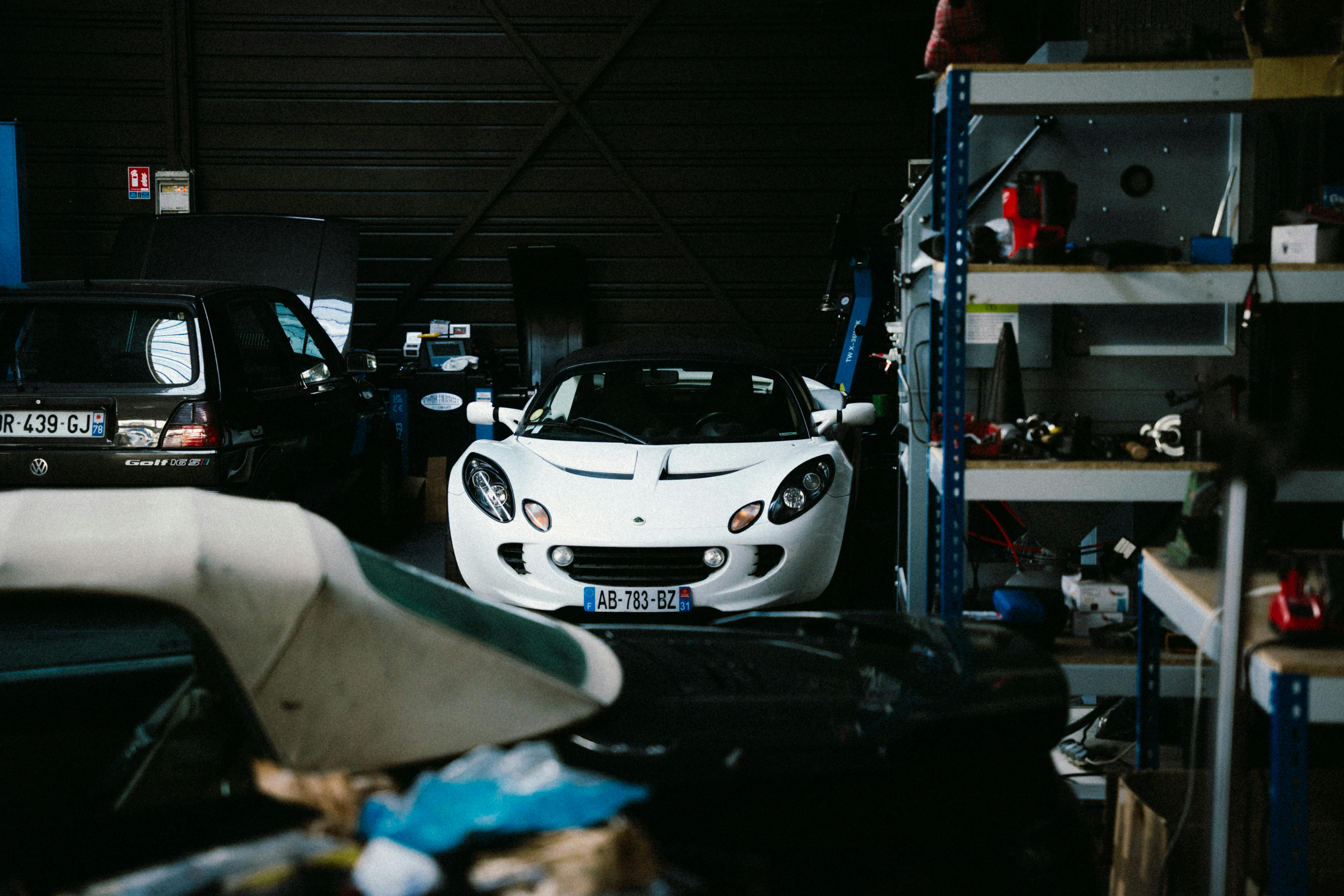 A classic white sports car is parked inside a dimly lit garage in Montigny-le-Bretonneux.