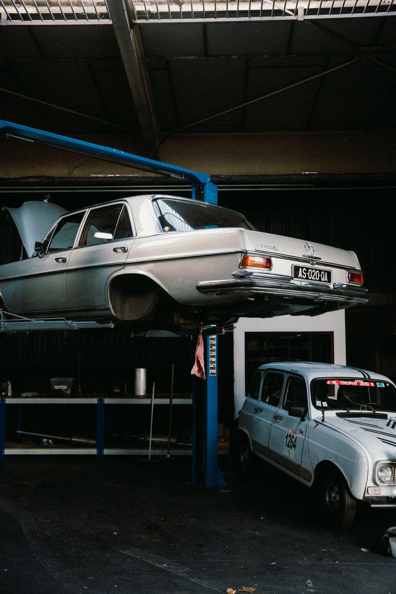 Classic cars on lifts in a French auto repair shop, showcasing vintage automobile restoration.