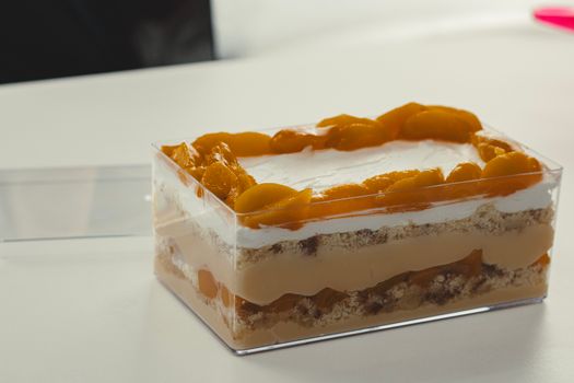 Enticing layered peach dessert with cream and biscuits in a clear container.