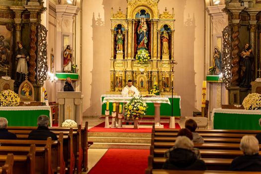 A priest conducting a Catholic mass inside a historic church in Garešnica, Croatia.