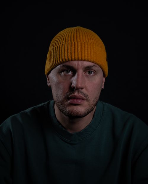 Free Studio portrait of a man wearing a yellow beanie, set against a dark background. Stock Photo