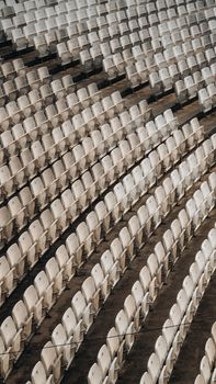 A pattern of empty white chairs in an outdoor stadium capturing repetition and symmetry.