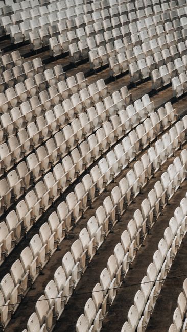 A pattern of empty white chairs in an outdoor stadium capturing repetition and symmetry.