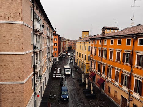 A captivating street view in Modena, Italy, showcases colorful buildings on a rainy day.