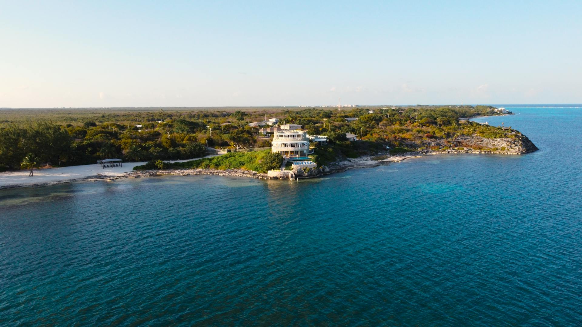 A scenic aerial view of a luxury beachfront estate in Grand Cayman with lush greenery and azure waters.