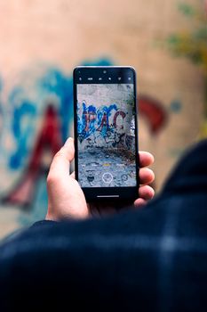 Close-up of a smartphone capturing vibrant street graffiti art in Tabriz, Iran.