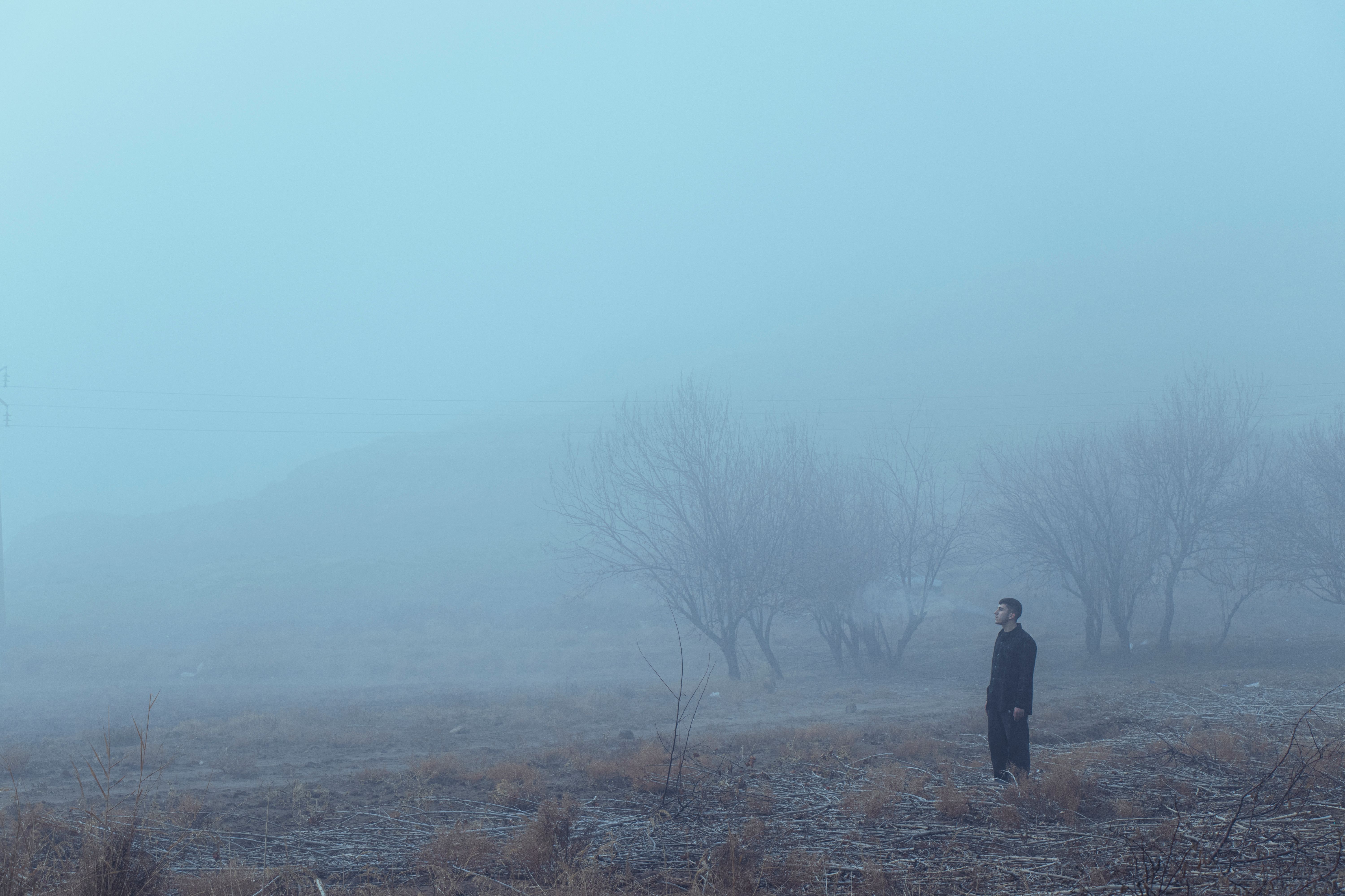 Moody portrait of a lone figure standing in a foggy field in Tabriz, Iran.