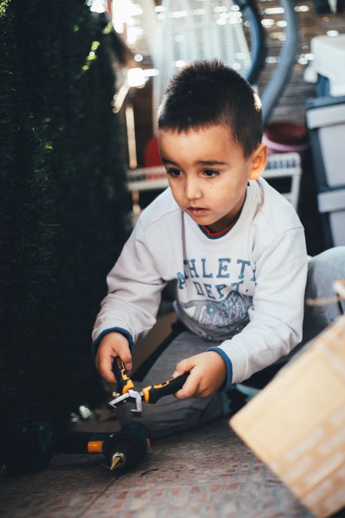 Free Young child engaging with toy tools indoors, showcasing curiosity and learning. Stock Photo