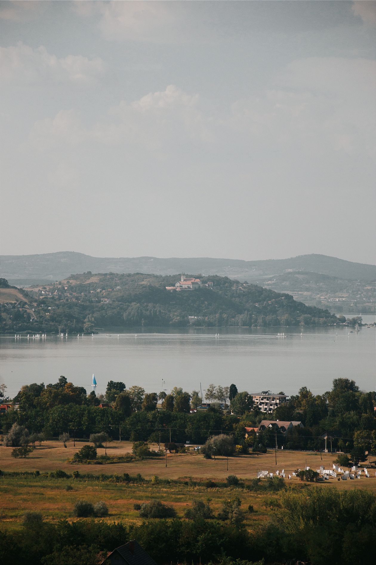 Mặt hồ Balaton phẳng lặng ở Hungary với dãy đồi xa mờ dưới bầu trời trong