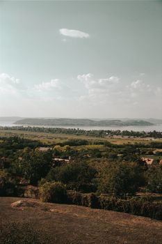 A serene view of the Hungarian countryside with lush greenery and a distant river under a clear sky. - Fotografer Sidoarjo