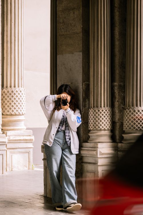 Free Woman photographing urban architecture with columns in city setting. Stock Photo