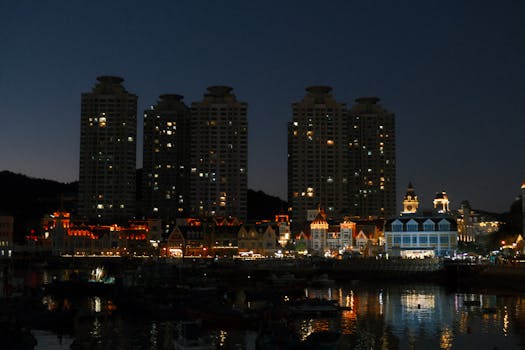 Vibrant city skyline and waterfront reflecting lights at night, creating a serene urban scene.