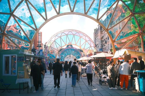 Free A bustling street market with colorful geometric arches and diverse crowd enjoying a sunny day. Stock Photo
