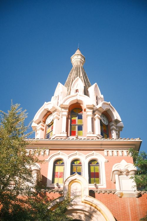 Free Elegant Gothic Revival tower with colorful stained glass under a blue sky. Stock Photo