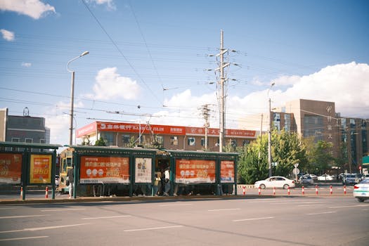 Street view of a busy bus stop with a cityscape backdrop on a sunny day.