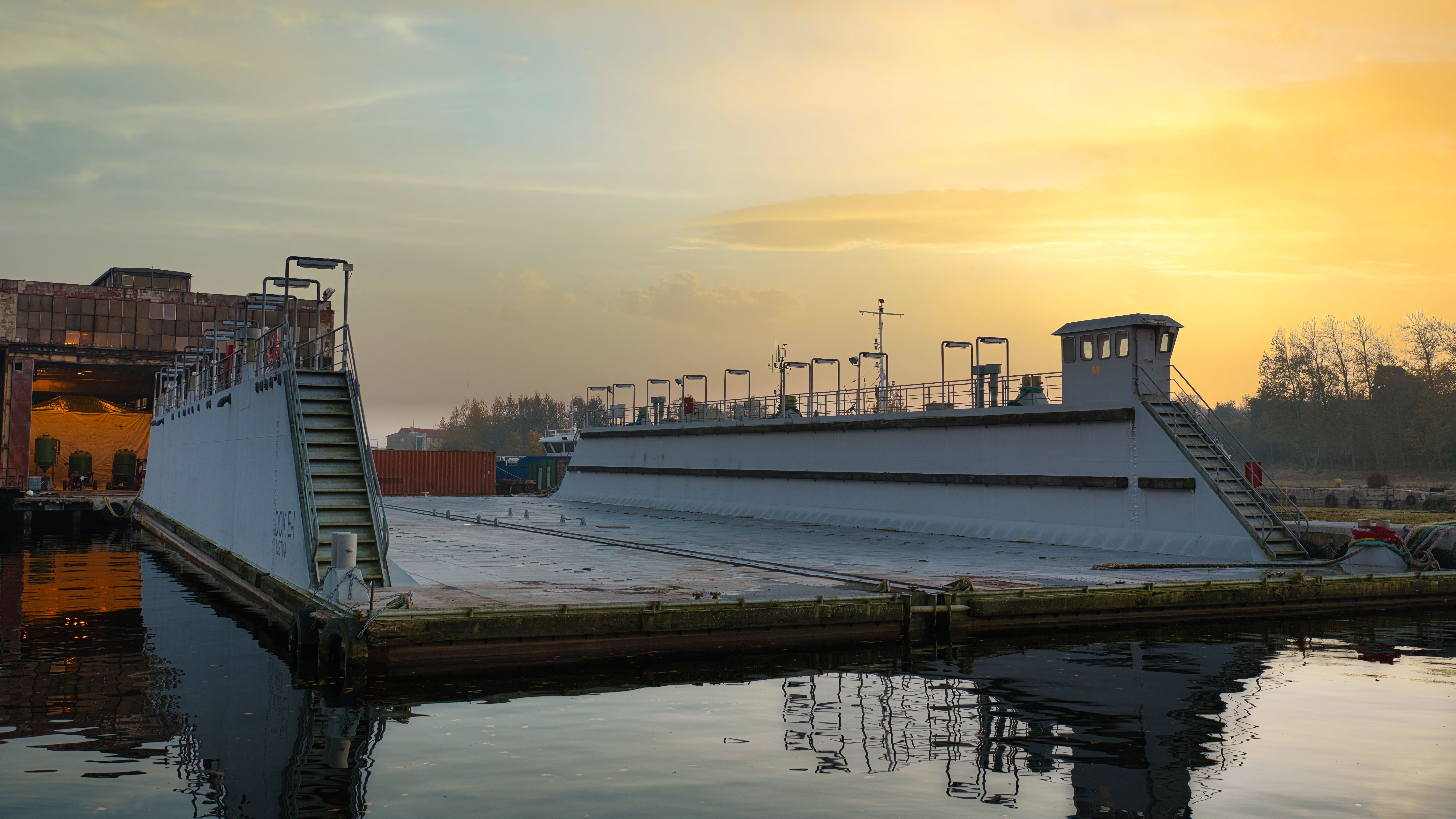 Large ship docked at a harbor during a serene sunset.