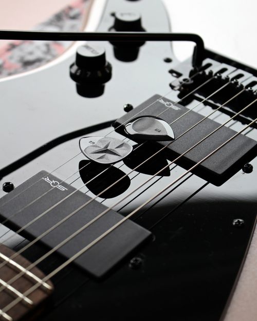 Free Detailed shot of a black electric guitar with various picks resting on the strings. Stock Photo