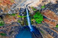 在印度尼西亚西爪哇省，一张迷人的航拍照片捕捉到瀑布落入岩石池的景象，四周被郁郁葱葱的绿色植物环绕