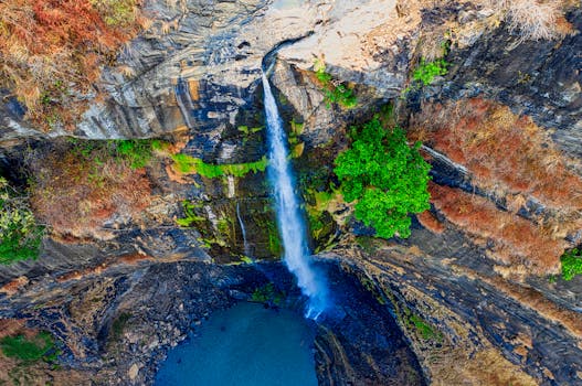 在印度尼西亚西爪哇省，一张迷人的航拍照片捕捉到瀑布落入岩石池的景象，四周被郁郁葱葱的绿色植物环绕