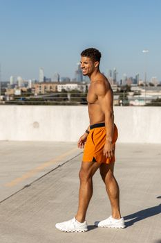 A fit male in orange shorts enjoying rooftop view of Austin skyline.