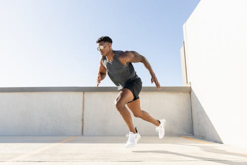 Free Dynamic image of a man sprinting on a building rooftop, showcasing athleticism and urban lifestyle. Stock Photo