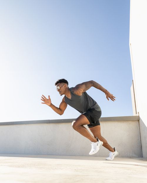 Free Energetic athlete running on a rooftop in Austin with clear sky background. Stock Photo