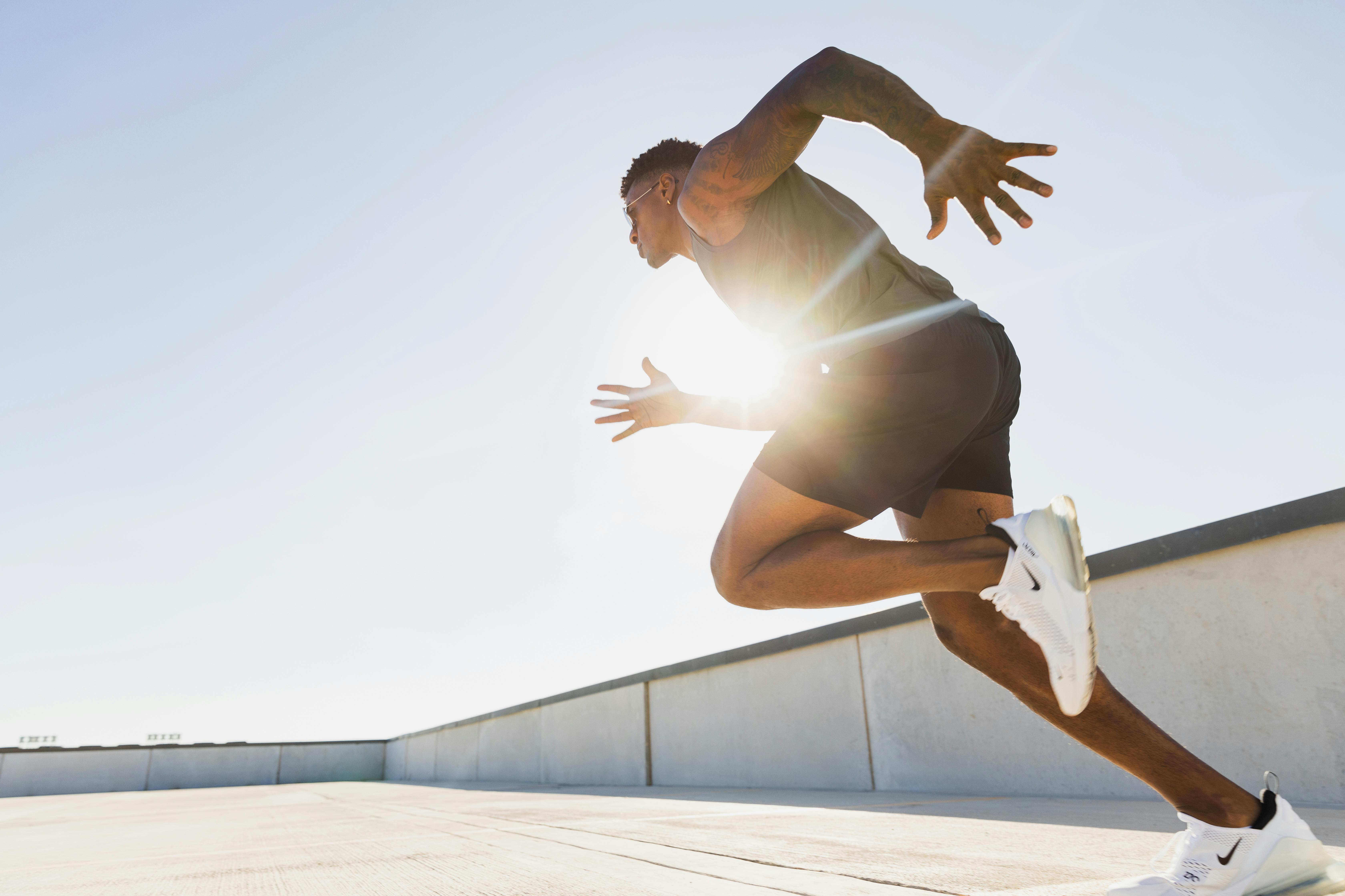 Dynamic side profile of an athletic man sprinting on a rooftop in Austin, Texas at sunrise.