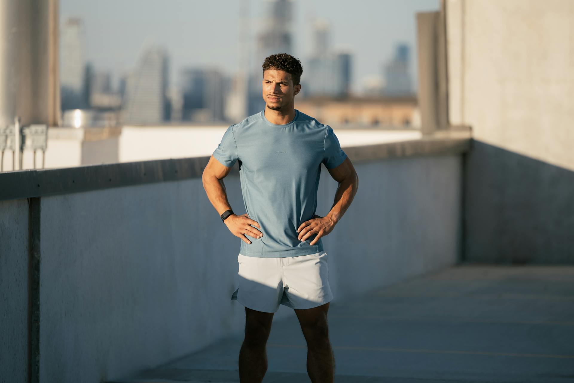 Man in athleisure attire doing workout on Austin rooftop with city skyline background.